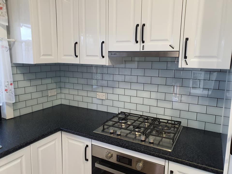 Glass splash back covering subway style tiles in a kitchen.
